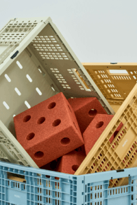 Close-up of green, yellow and blue MODU crates stacked at angles, with orange modular blocks inside the green crate.