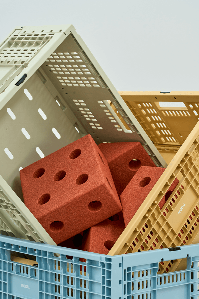 Close-up of green, yellow and blue MODU crates stacked at angles, with orange modular blocks inside the green crate.