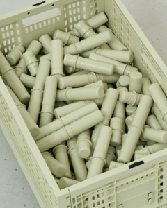 Close-up from above of a sage-green MODU crate filled with matching cylindrical connectors.