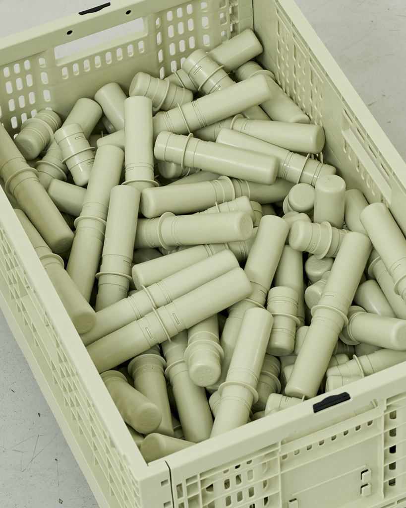 Close-up from above of a sage-green MODU crate filled with matching cylindrical connectors.