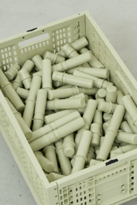 Close-up from above of a sage-green MODU crate filled with matching cylindrical connectors.