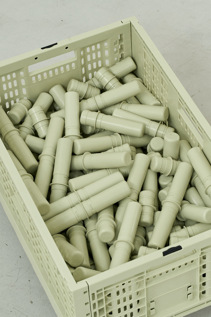Close-up from above of a sage-green MODU crate filled with matching cylindrical connectors.