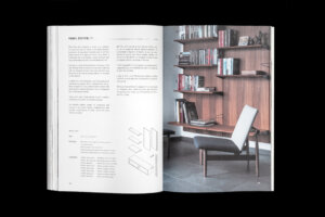 House of Finn Juhl catalogue spread with furniture drawings and text beside a lounge chair photographed in front of bookshelves.