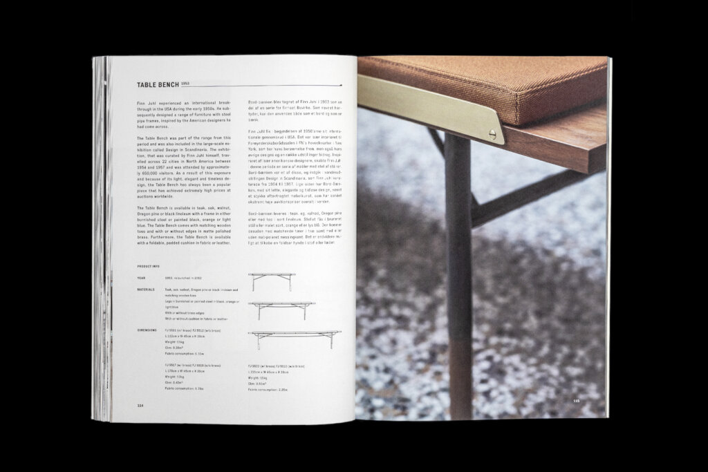 House of Finn Juhl catalogue spread with text and technical drawings beside a close-up of a wooden table edge and dark legs.