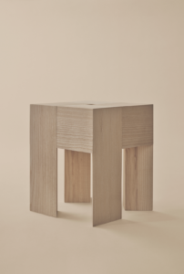 Angular wooden Karakter TriAngle table with broad legs and visible grain against a beige background.