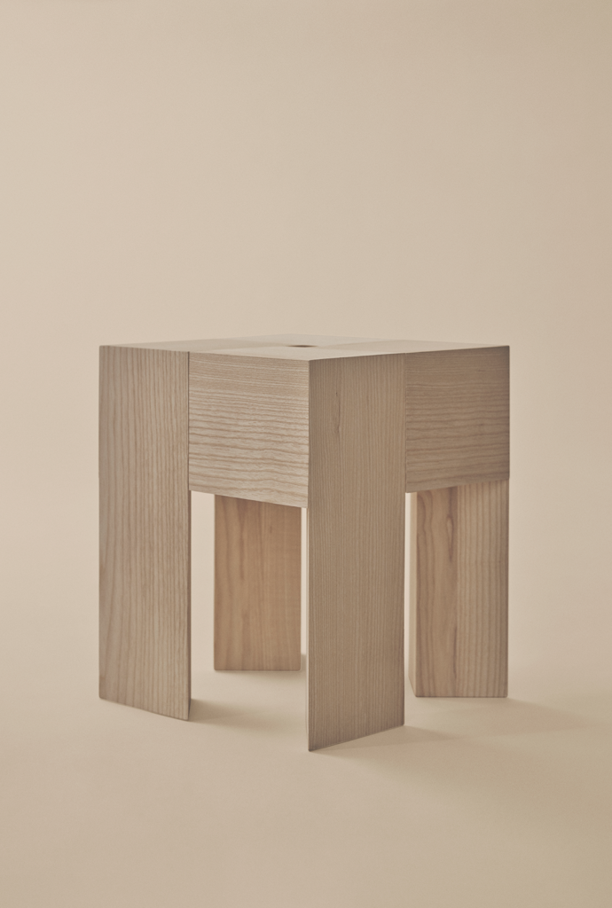 Angular wooden Karakter TriAngle table with broad legs and visible grain against a beige background.