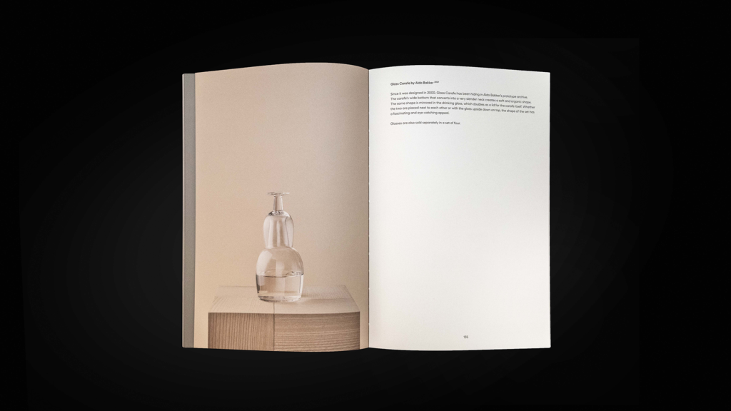 Karakter catalogue spread pairing a glass carafe photograph on a beige background with a white text page.