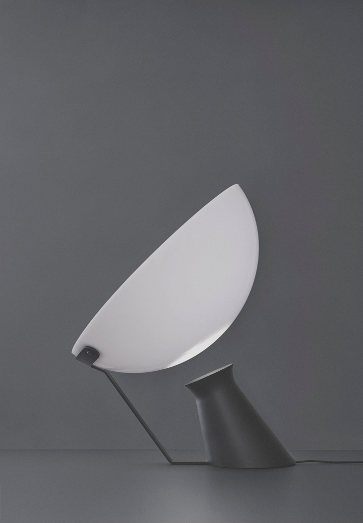 Karakter Aida lamp with a curved white shade tilted above a black base against a grey background.