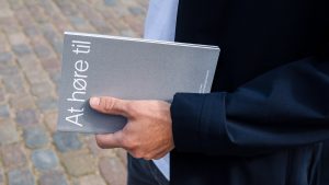 The silver At Høre Til catalogue held in a hand